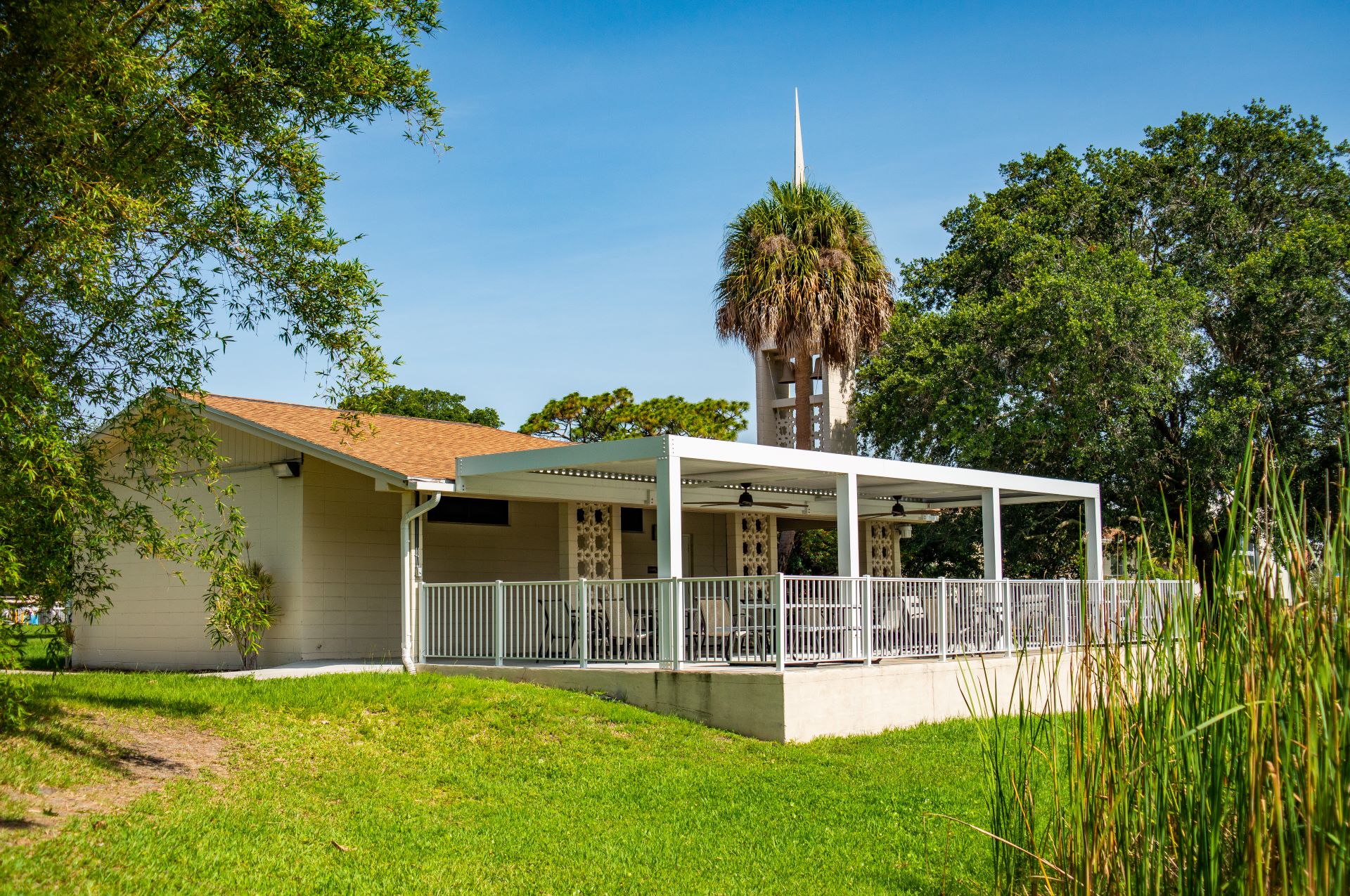 Side view of All Faiths Center at Florida Tech, featuring the patio area with seating, surrounded by greenery and trees