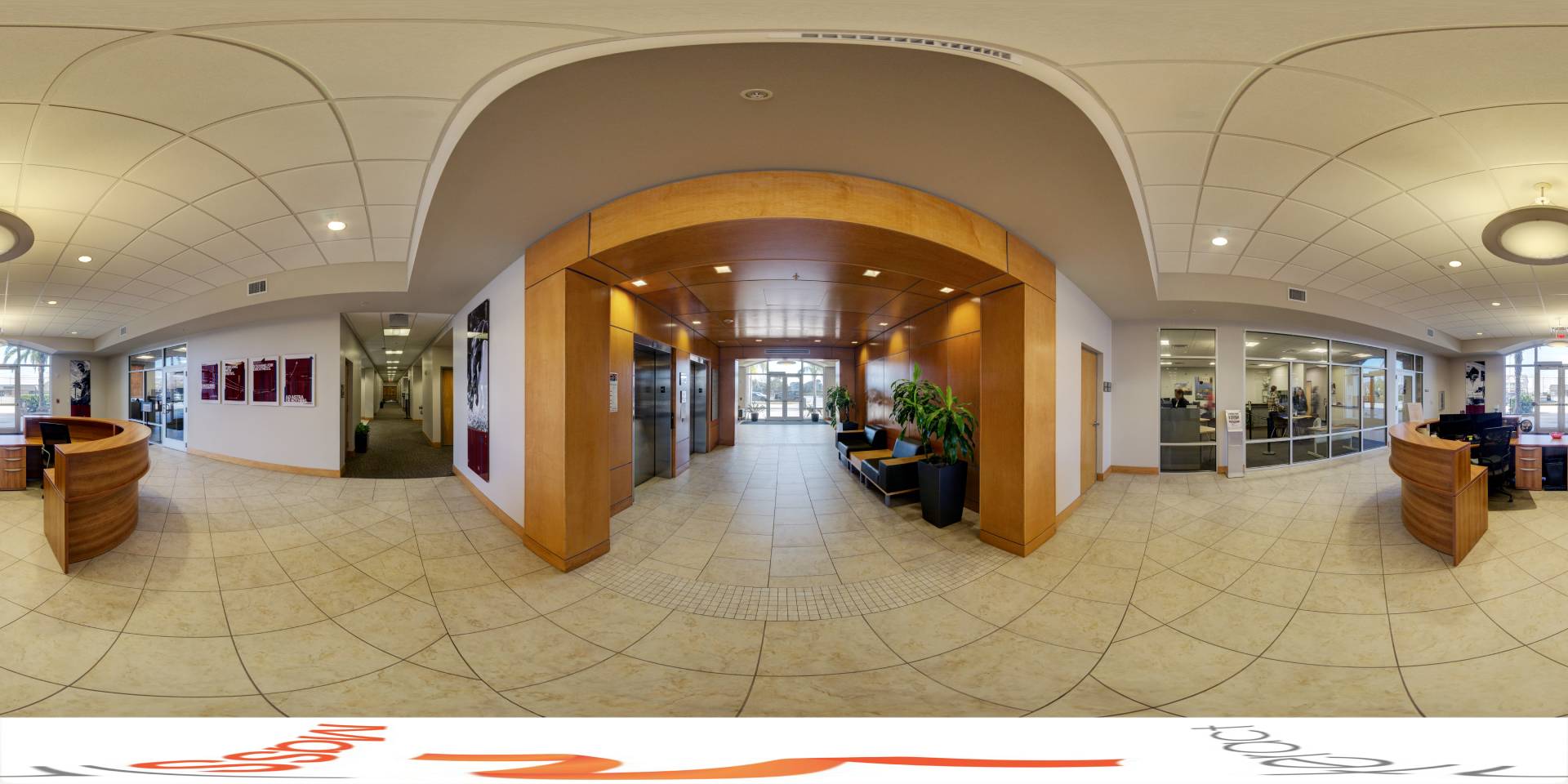 Panoramic interior view of a community center lobby with a reception desk, wooden accents, and seating areas