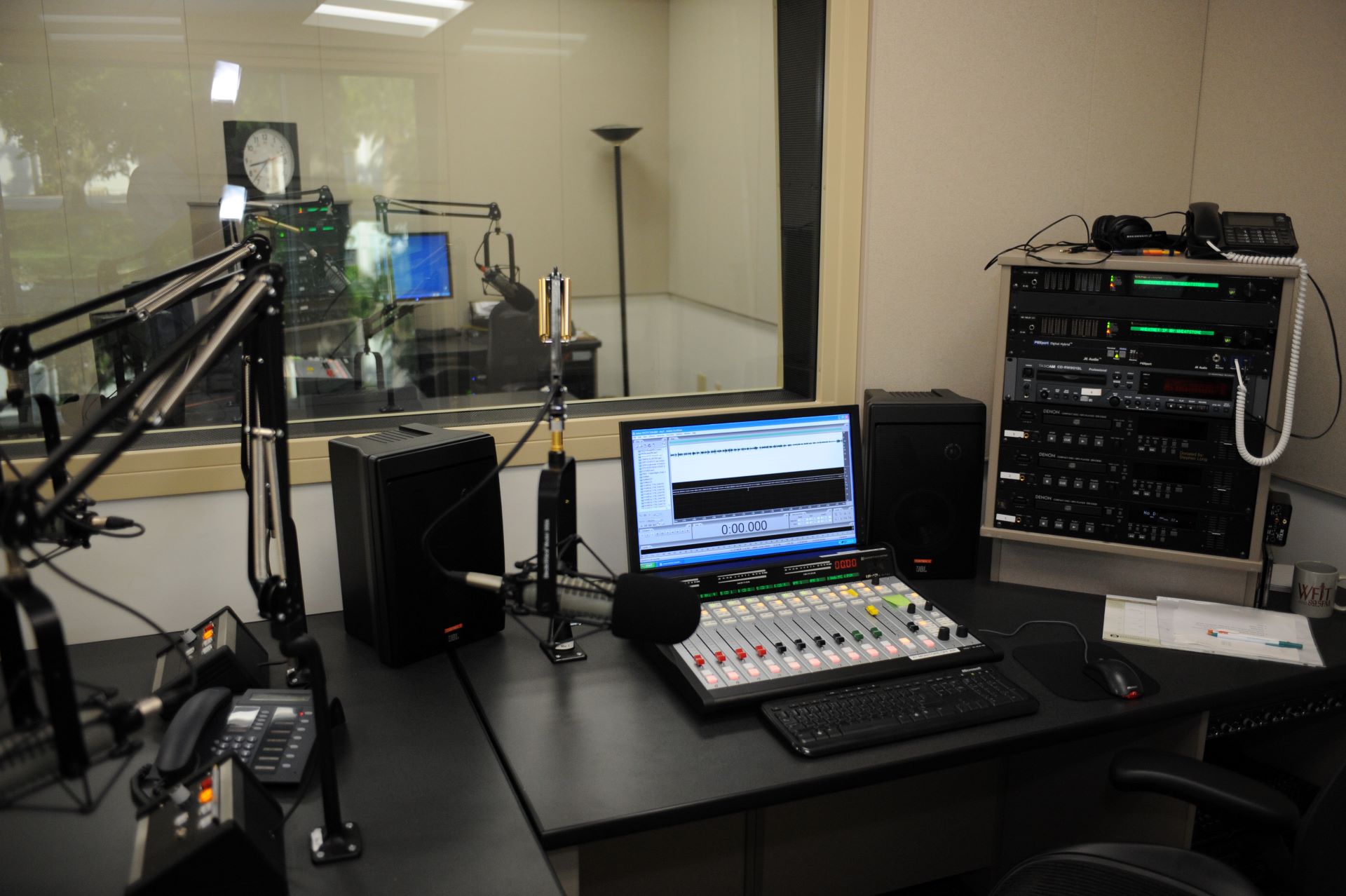 Inside the WFIT Broadcast Center at Florida Tech, showcasing the recording studio with microphones, mixing consoles, computer screens, and other audio equipment