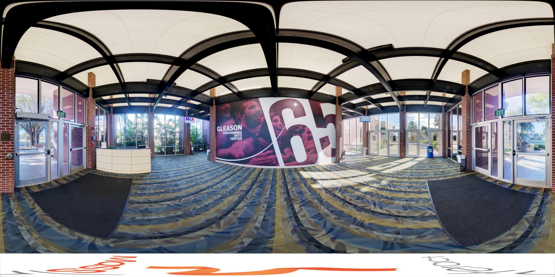 Panoramic view of the spacious lobby at the Gleason Performing Arts Center, featuring modern design elements, large windows, and a prominent mural celebrating the center's legacy