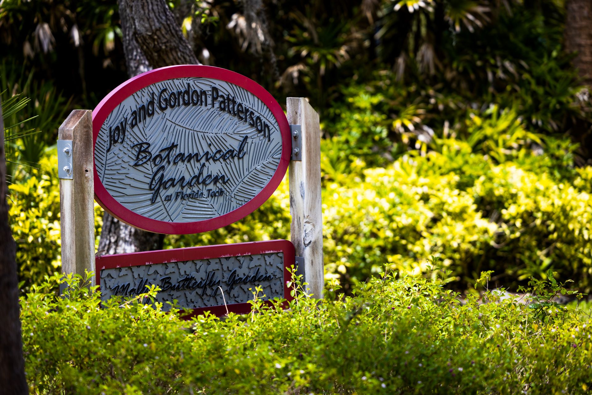 Signage for the Joy and Gordon Patterson Botanical Garden at Florida Tech, surrounded by lush green foliage