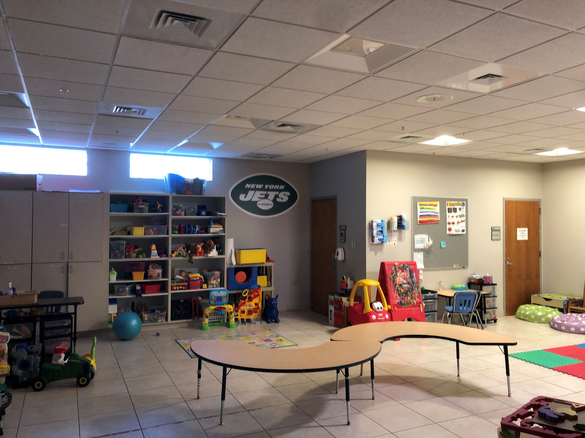 A playroom with toys on shelves and the floor, illuminated by soft light