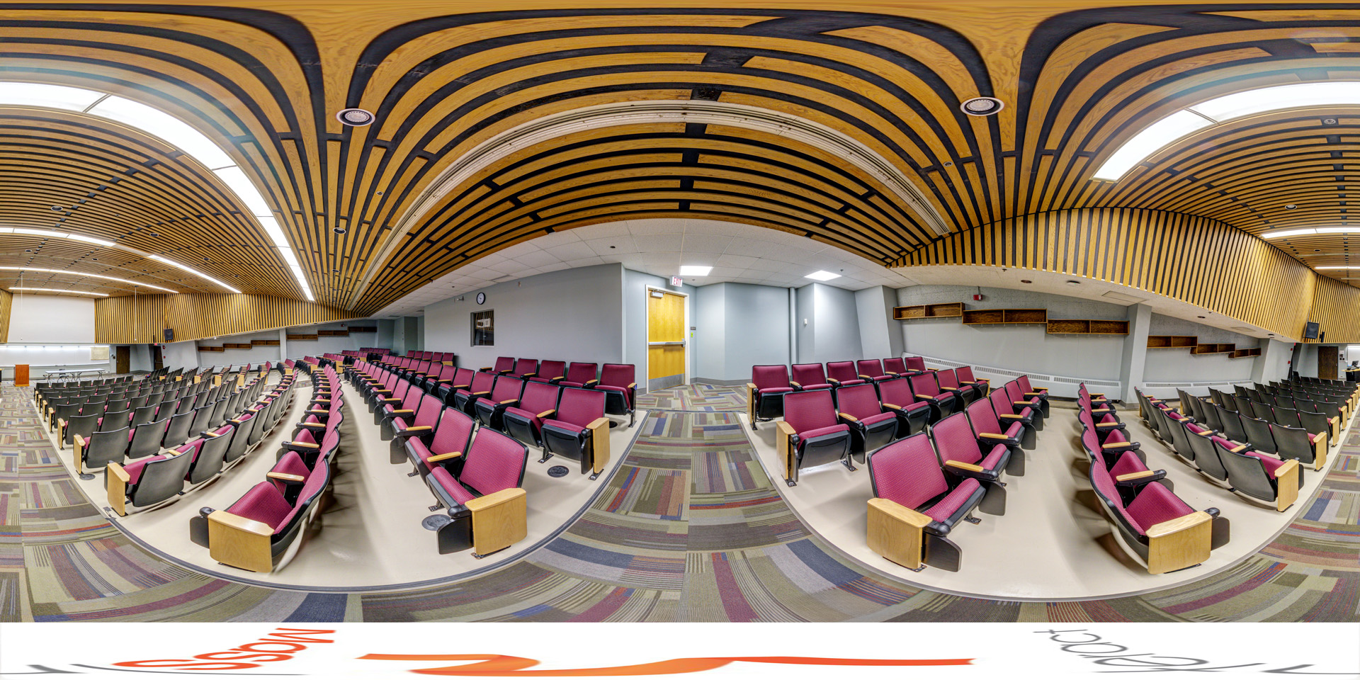 Panoramic view of a lecture hall with tiered seating, purple chairs, and a wooden ceiling with curved slats.