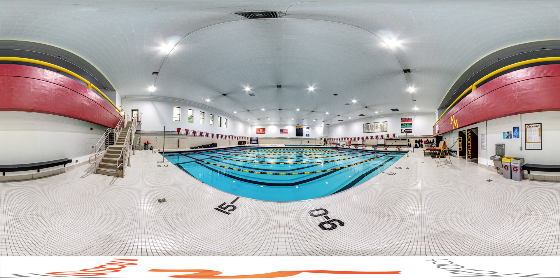 Panoramic view of the competition pool area with lane dividers, seating, and a red balcony section along the upper walls.