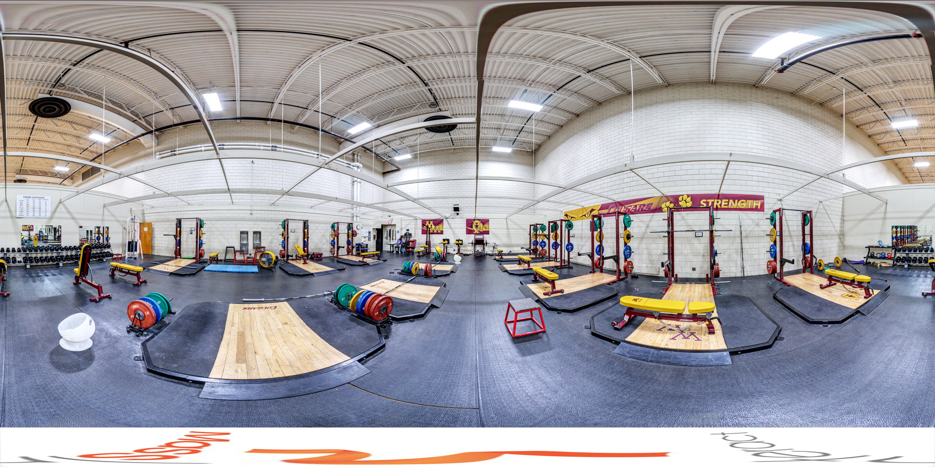 Panoramic view of a wide view of a weight room featuring various lifting platforms, benches, and weights, with a banner labeled 'Cougar Strength.' 