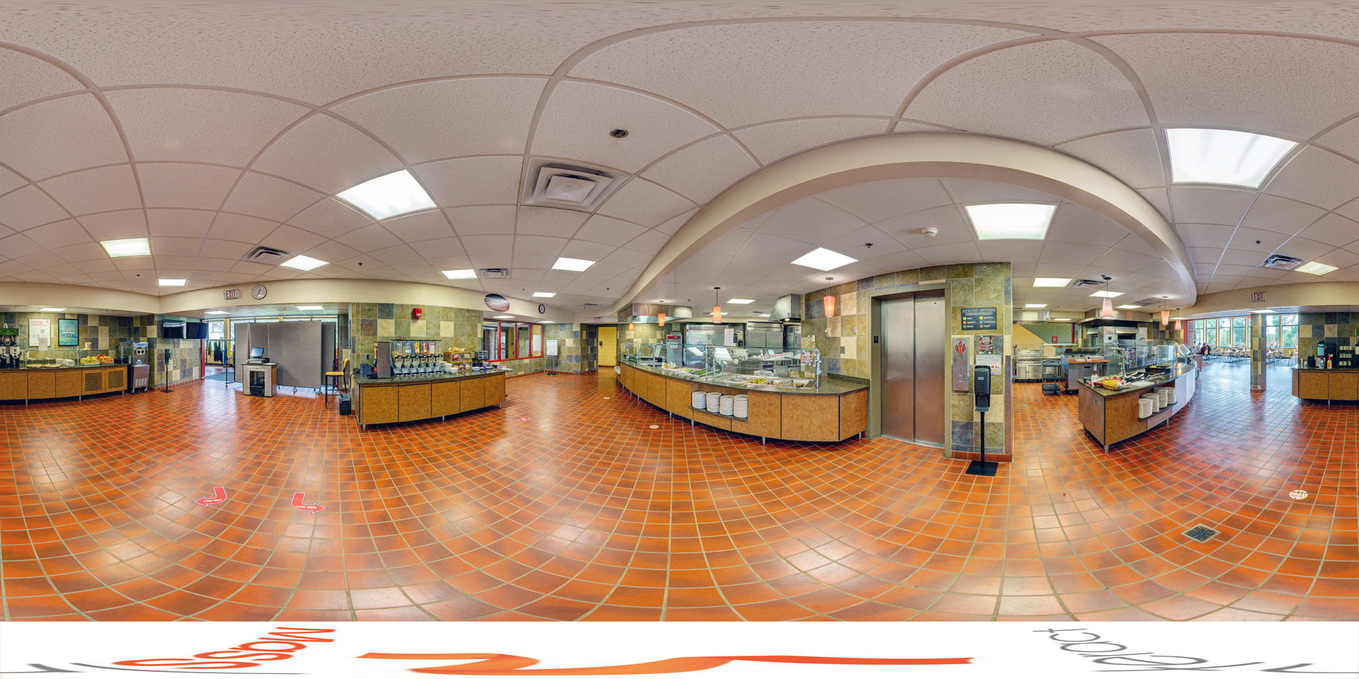 Panoramic view of a spacious dining hall serving area with a red-tiled floor, multiple food stations, and beverage dispensers. The ceiling features recessed lighting, and the area opens into a seating section in the background.